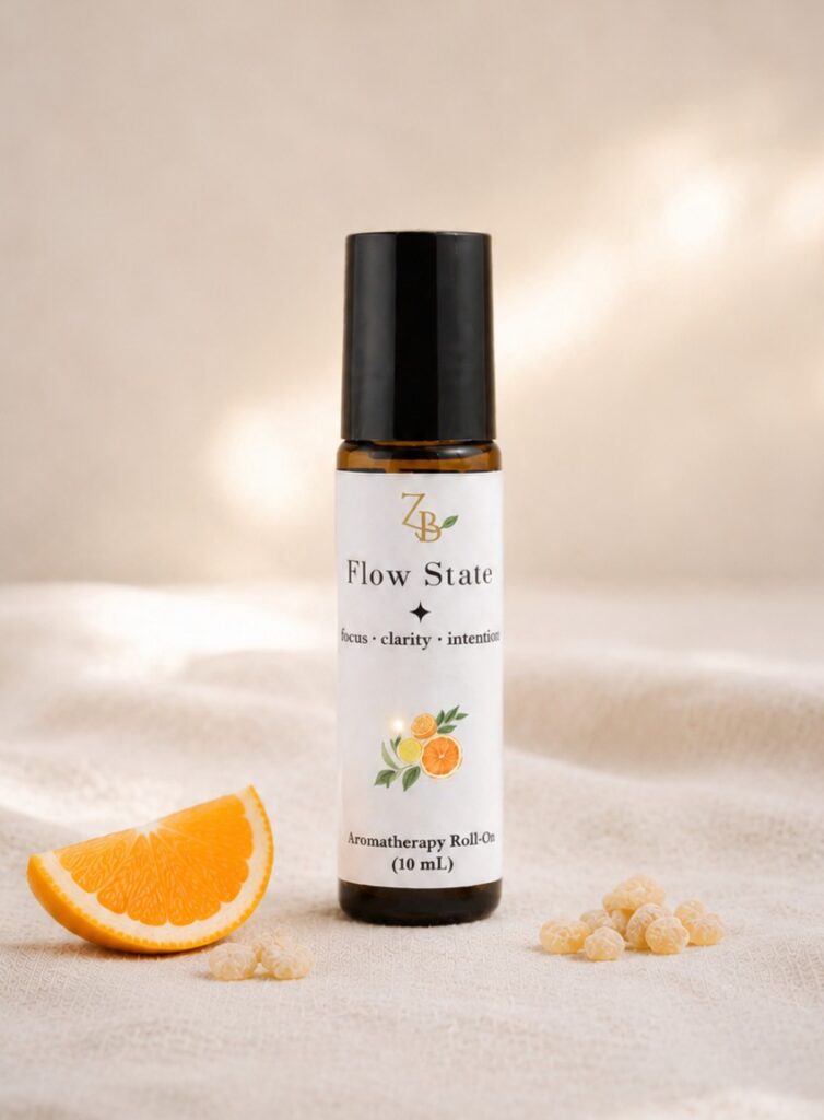Flow State aromatherapy roll-on beside fresh orange and frankincense resin on soft neutral fabric