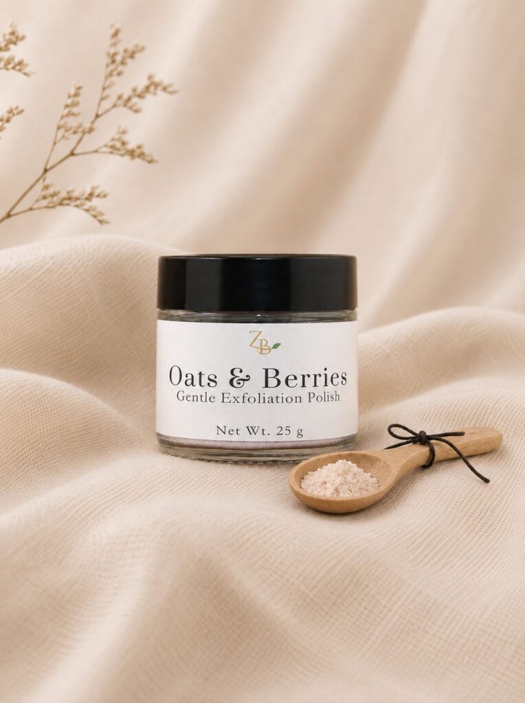 Oats & Berries gentle exfoliation polish beside a wooden spoon of pale pink powder on cream linen