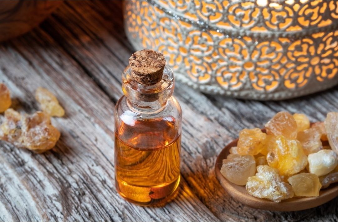 Frankincense resin and essential oil beside a glowing lantern