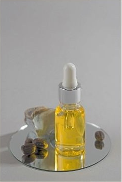 Dropper bottle of golden jojoba oil with jojoba seeds
