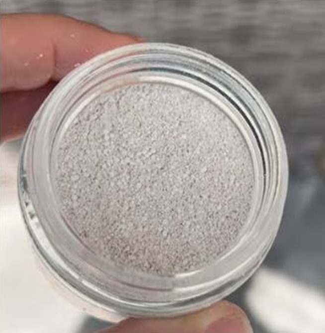 Open glass jar of finely milled oat powder held in hand