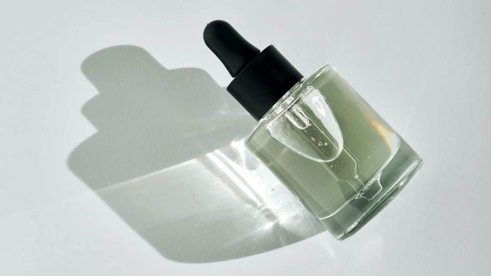 Glass dropper bottle of clear squalane casting a soft shadow